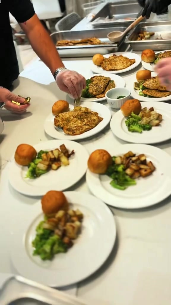 Roasted chicken dinner plates being prepared with potatoes and broccoli